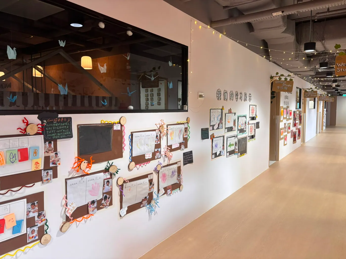 A bright learning corridor lined with children's project work and studio signage